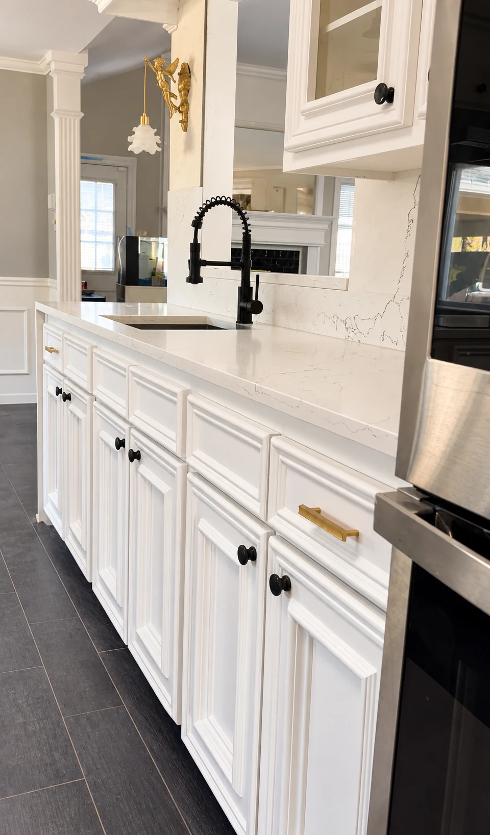 White kitchen cabinets and veined stone counters with a single black spring faucet